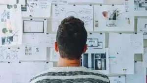 Trabajador autónomo observando un panel lleno de notas y diagramas para planificar un proyecto.
