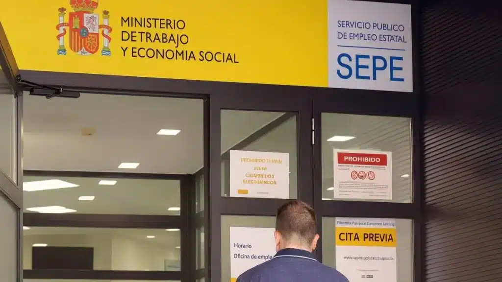 Entrada de una oficina del SEPE con un usuario esperando para acceder.