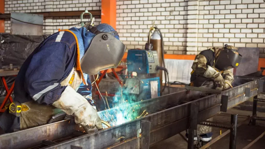 Trabajadores realizando labores de soldadura en un taller industrial.